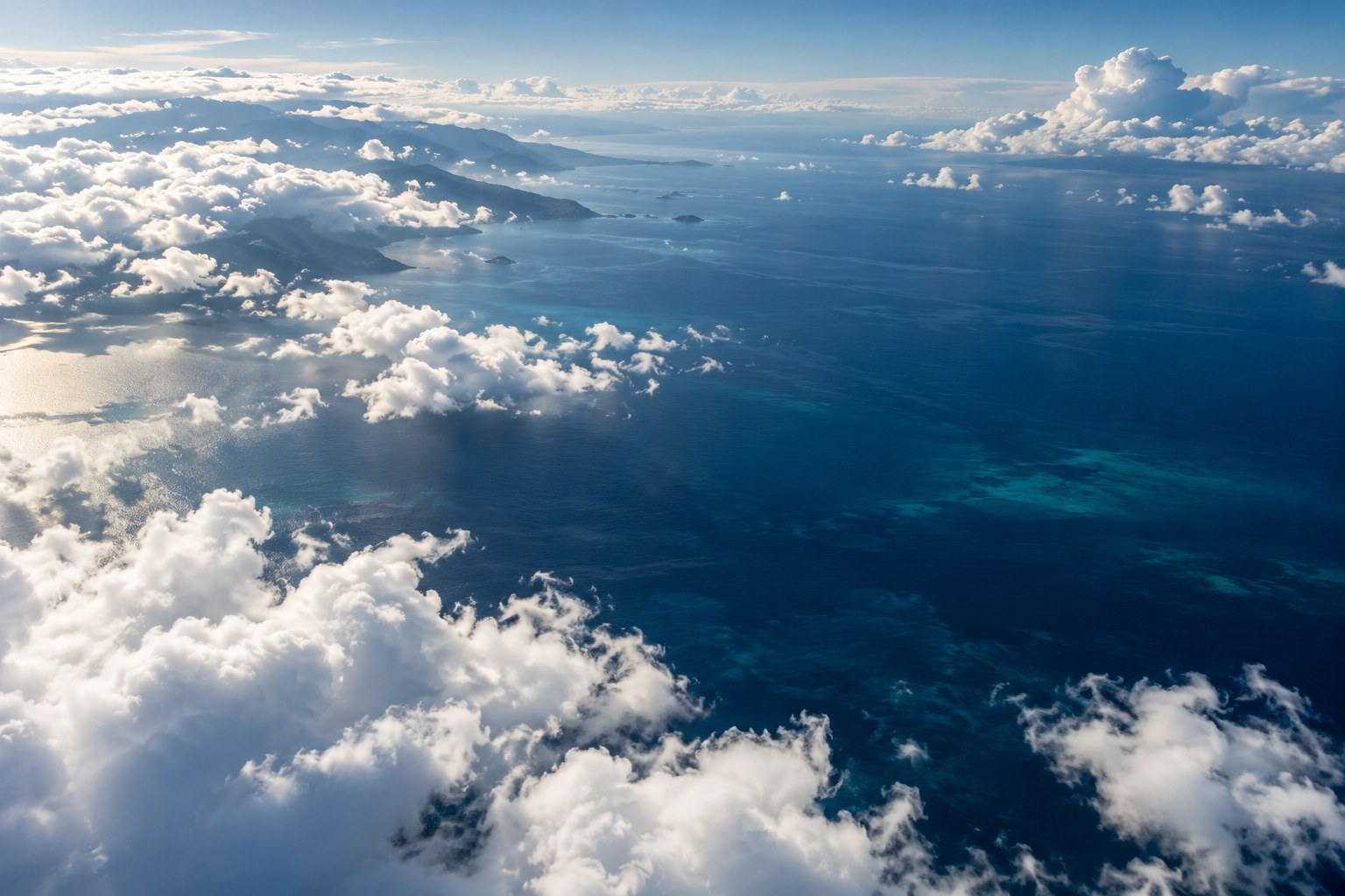 Sunlit clouds above a deep blue sea